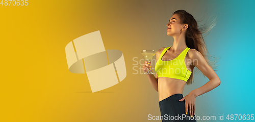 Image of Fashion portrait of young fit and sportive woman drinking cocktail on gradient background. Perfect body ready for summertime. Flyer with copyspace.