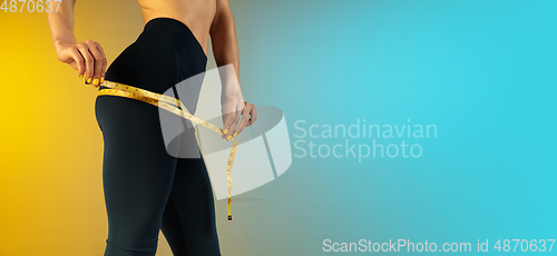 Image of Close up of young and sportive woman with fit belly and measurer on gradient background. Perfect body ready for summertime. Flyer with copyspace.