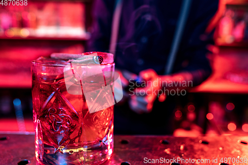 Image of Close up of alcoholic cocktail, beverage, drink, prepared by professional barman in multicolored neon light