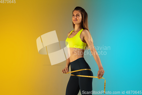 Image of Fashion portrait of young fit and sportive woman with measurer on gradient background. Perfect body ready for summertime.