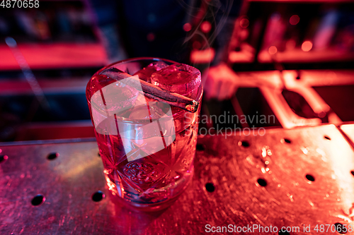 Image of Close up of alcoholic cocktail, beverage, drink, glass full of ice in multicolored neon light