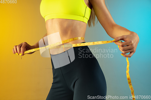 Image of Close up of young and sportive woman with fit belly and measurer on gradient background. Perfect body ready for summertime.