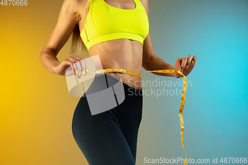 Image of Close up of young and sportive woman with fit belly and measurer on gradient background. Perfect body ready for summertime.