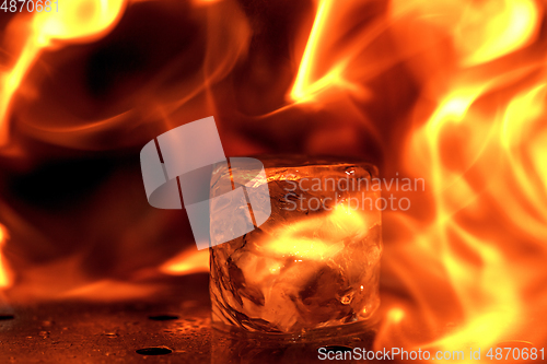 Image of Close up big melting piece of ice on the bar counter in fireflames on it, preparation for a cocktail