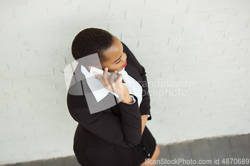 Image of African-american businesswoman in office attire smiling, looks confident and happy, successful