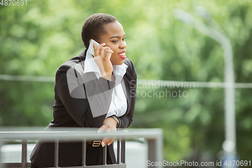 Image of African-american businesswoman in office attire smiling, looks confident and happy, successful