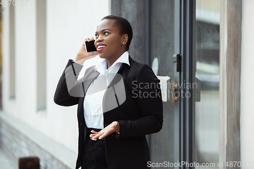 Image of African-american businesswoman in office attire smiling, looks confident and happy, successful