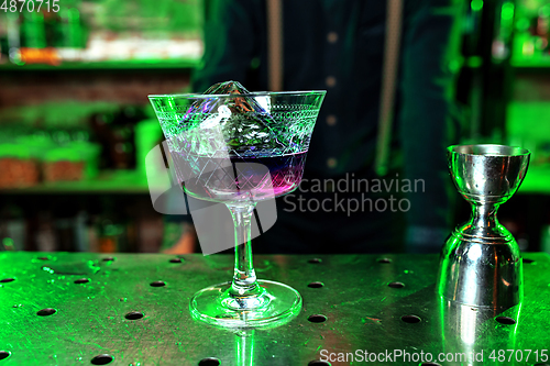 Image of Close up of alcoholic cocktail, beverage, drink, prepared by professional barman in multicolored neon light