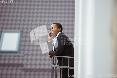 Image of African-american businesswoman in office attire smiling, looks confident and happy, successful