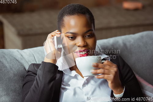 Image of African-american businesswoman in office attire smiling, looks confident and happy, successful