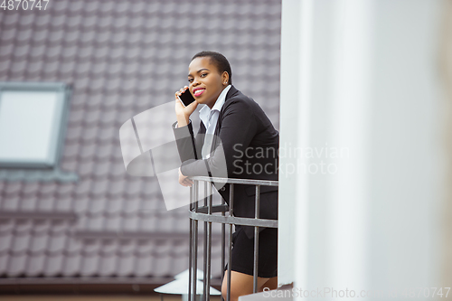 Image of African-american businesswoman in office attire smiling, looks confident and happy, successful