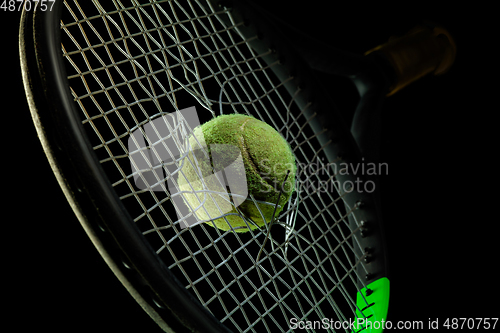 Image of Professional sport equipment isolated on black studio background. Tennis racket and ball.