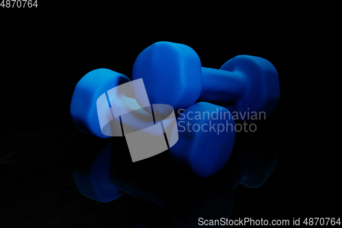 Image of Professional sport equipment isolated on black studio background. Blue gym weights.