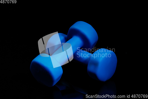 Image of Professional sport equipment isolated on black studio background. Blue gym weights.