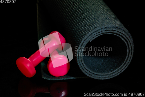 Image of Professional sport equipment isolated on black studio background. Exercise mat and weights.