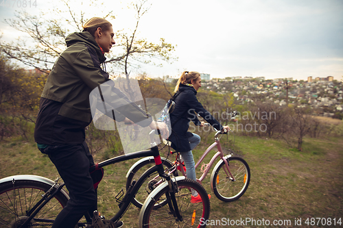 Image of Best friends having fun near countryside park, riding bikes, spending time healthy