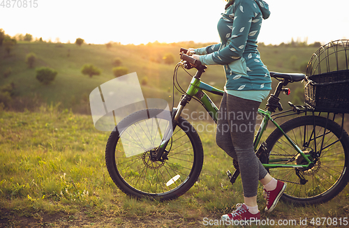 Image of Young woman having fun near countryside park, riding bike, traveling at spring day