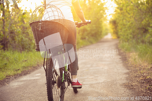 Image of Young woman having fun near countryside park, riding bike, traveling at spring day