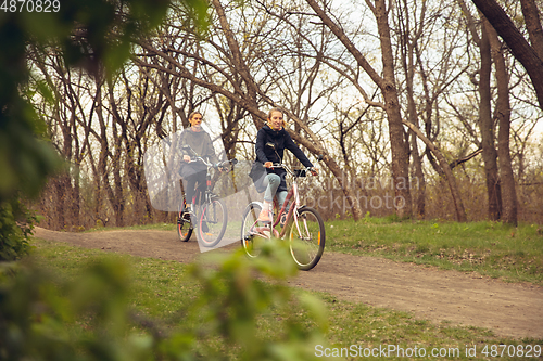 Image of Best friends having fun near countryside park, riding bikes, spending time healthy