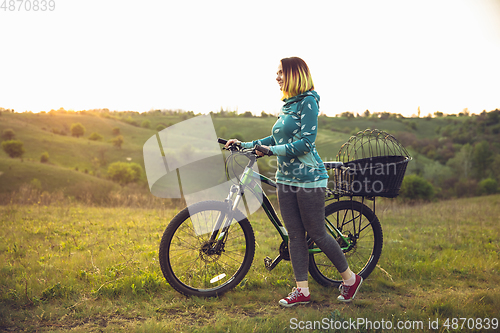 Image of Young woman having fun near countryside park, riding bike, traveling at spring day