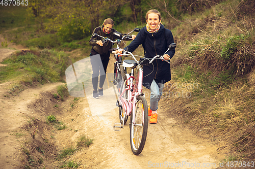 Image of Best friends having fun near countryside park, riding bikes, spending time healthy