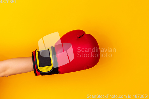 Image of Hand in boxing red glove isolated on yellow studio background with copyspace.