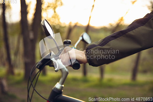 Image of Close up of young man having fun near countryside park, riding bike, traveling at spring day