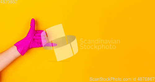 Image of Hand in pink rubber glove isolated on yellow studio background with copyspace. Flyer.