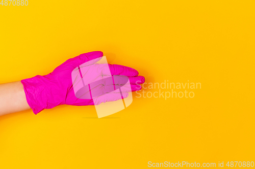 Image of Hand in pink rubber glove greeting isolated on yellow studio background with copyspace.