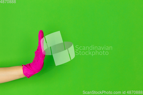 Image of Hand in pink rubber glove clapping isolated on green studio background with copyspace.