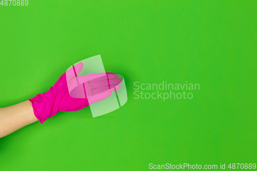 Image of Hand in pink rubber glove greeting isolated on green studio background with copyspace.