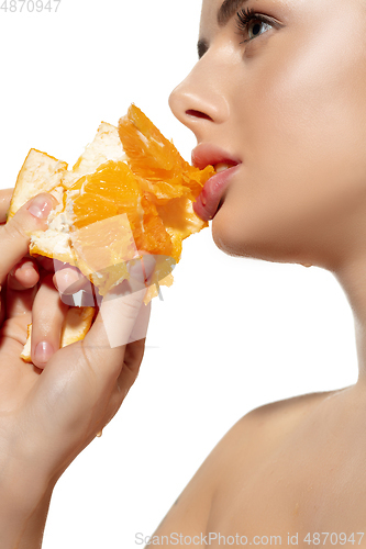 Image of Energy. Close up of beautiful young woman biting juicy orange over white background. Cosmetics and makeup, natural and eco treatment, skin care.