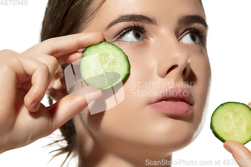 Image of Freshness. Close up of beautiful young woman with cucumber\'s slices on her face on white background. Cosmetics and makeup, natural and eco treatment, skin care.