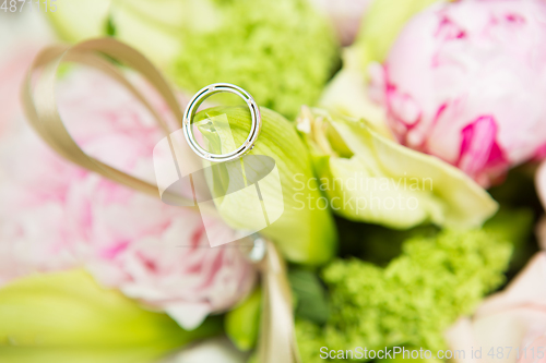 Image of wedding rings lie on a beautiful bouquet as bridal accessories