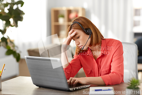 Image of sad woman with headset and laptop working at home