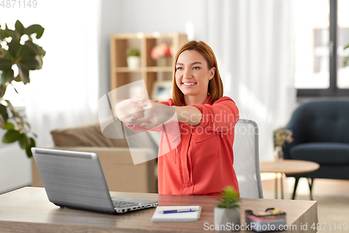 Image of happy woman stretching arms at home office