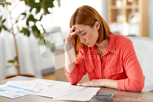 Image of woman with calculator and papers working at home