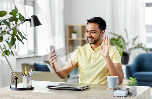 Image of indian man having video call on smartphone at home