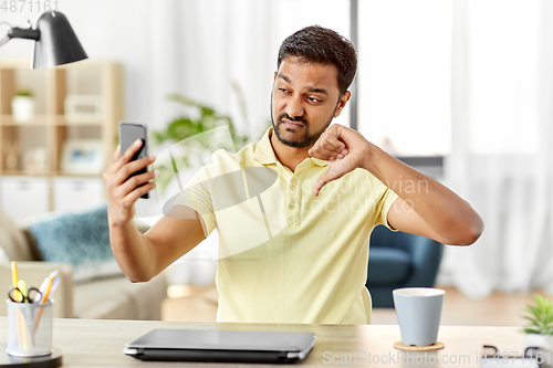 Image of indian man having video call on smartphone at home