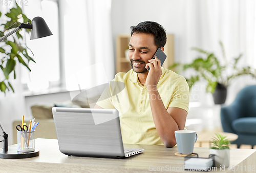 Image of happy man calling on smartphone at home office