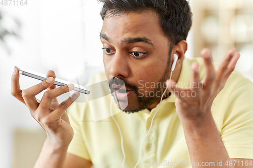 Image of angry man with earphones calling on smartphone