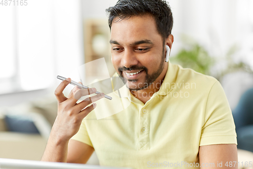 Image of man recording voice on smartphone at home office