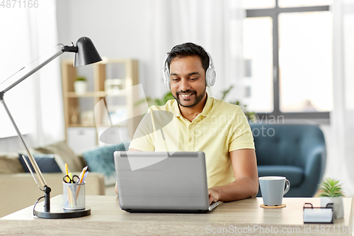 Image of man in headphones with laptop working at home