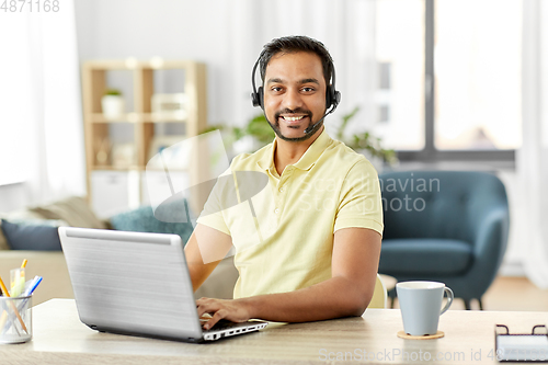 Image of indian man with headset and laptop working at home