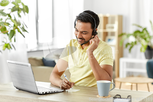 Image of indian man with headset and laptop working at home