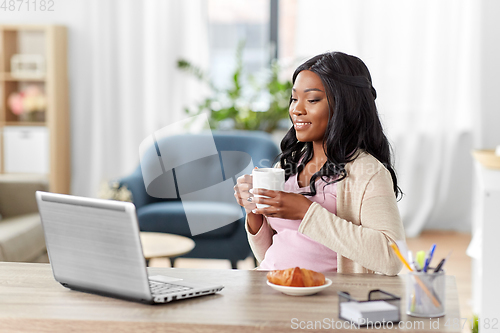 Image of happy woman with laptop and coffee at home office