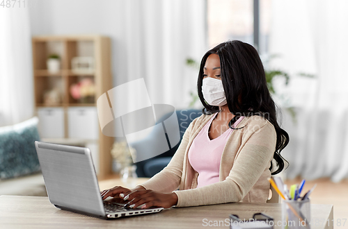 Image of woman in mask with laptop working at home office