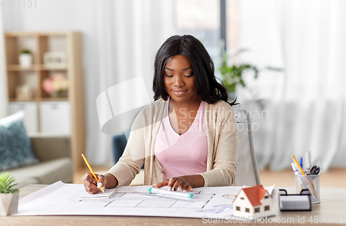 Image of female architect with house model and blueprint