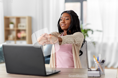 Image of african american woman stretching at home office