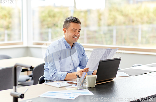 Image of man with laptop and papers working at home office
